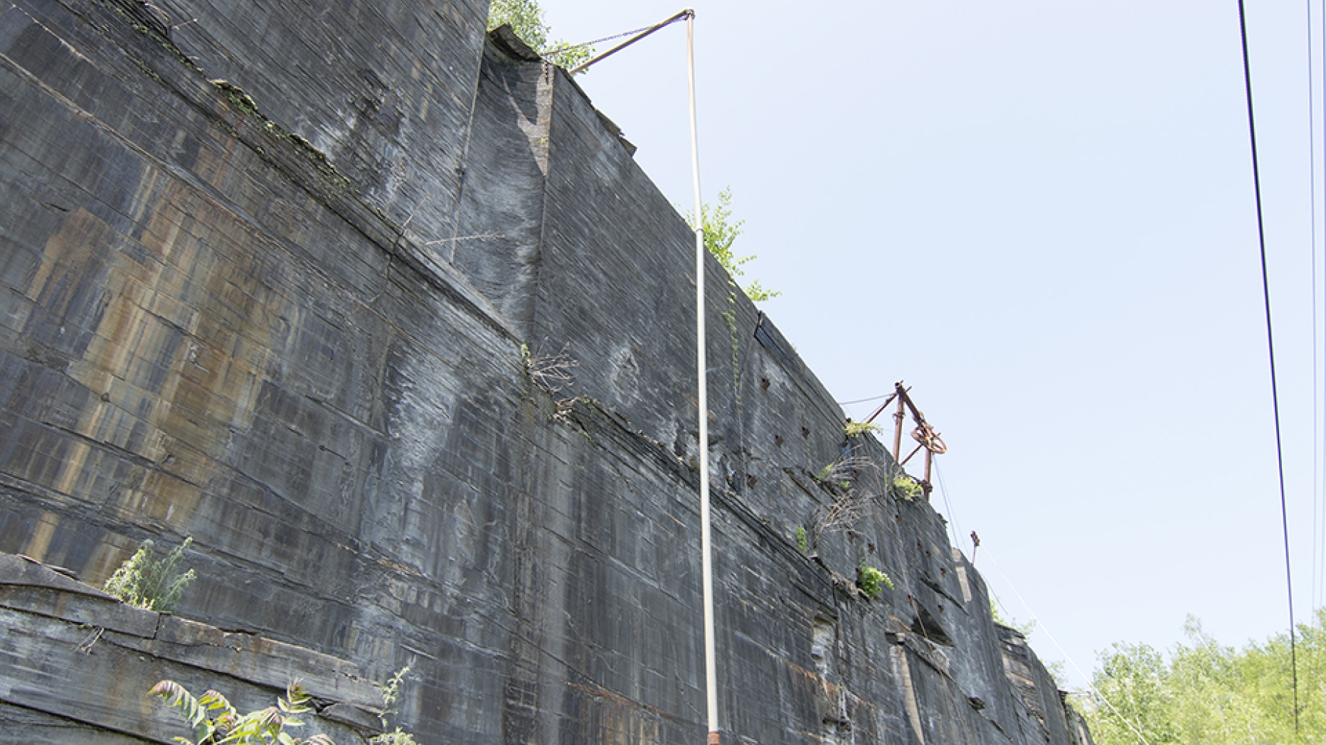 Walls of a quarry with cranes at the top.