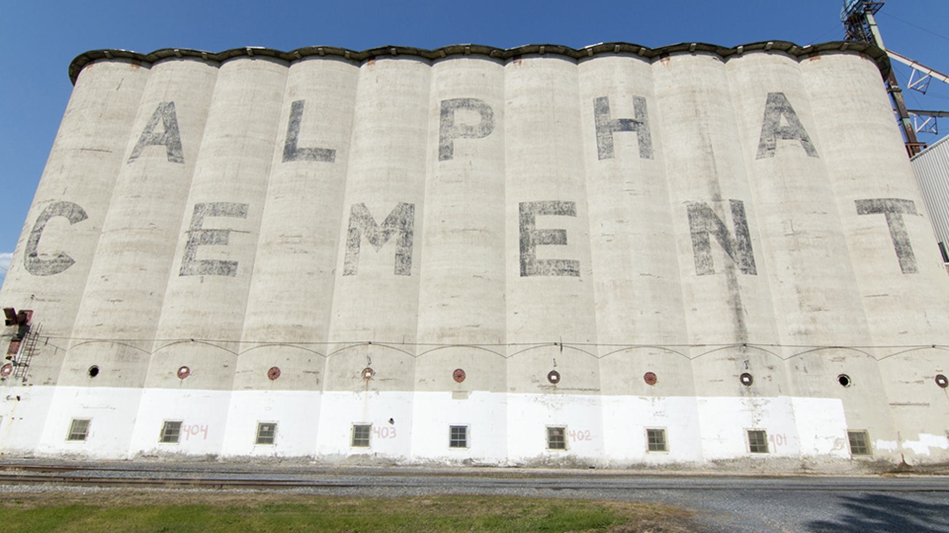 Cement silos with ALPHA CEMENT painted on the side.