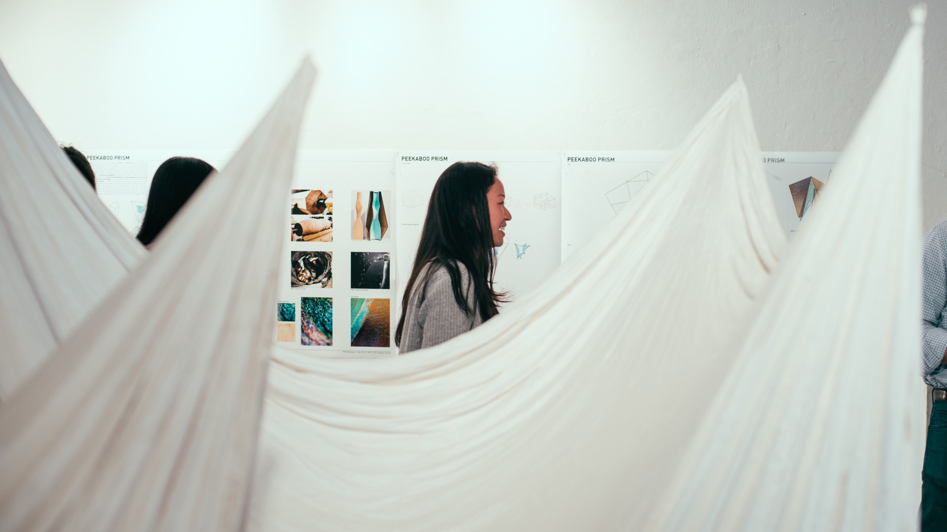 Art installation made from draped sheets with viewers walking around in the background.