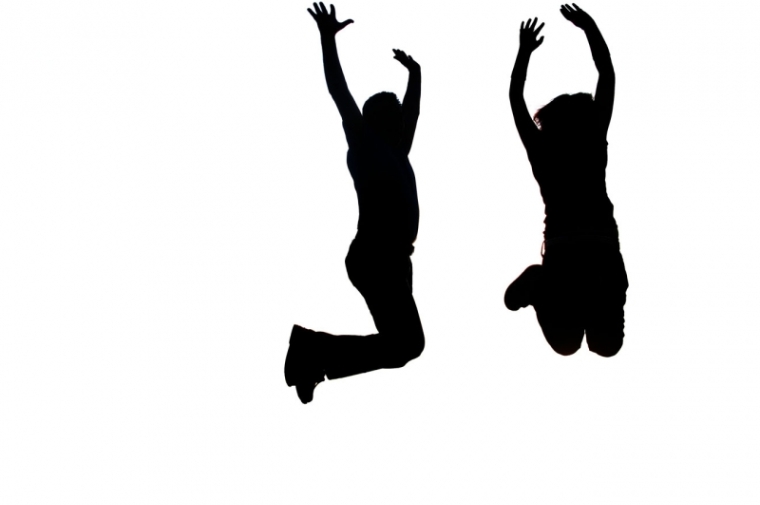 Silhouettes of two people jumping