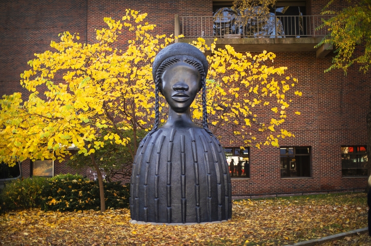 Brick House, a 16 foot bronze sculpture of an African American woman figure in front of yellow fall leaves