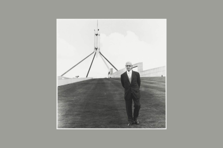 black and white photo of man in suit in front of abstract structure