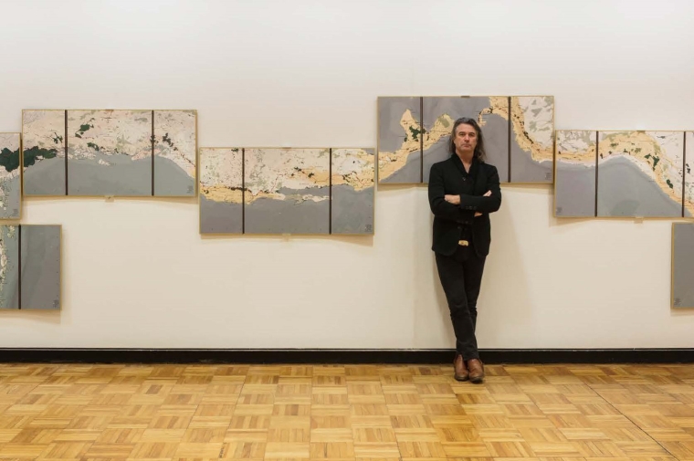 Image of Richard Weller standing in front of panels of his work