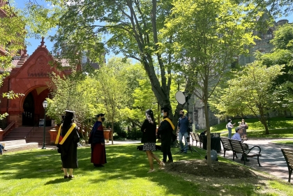 Photo of graduating students in their academic regalia for a photoshoot on campus.