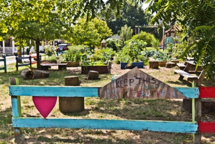 Sign saying "keep this park beautiful" with vegetable garden behind it
