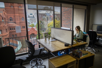 Student working at studio desk next to a large window looking out at Fisher Fine Arts building.