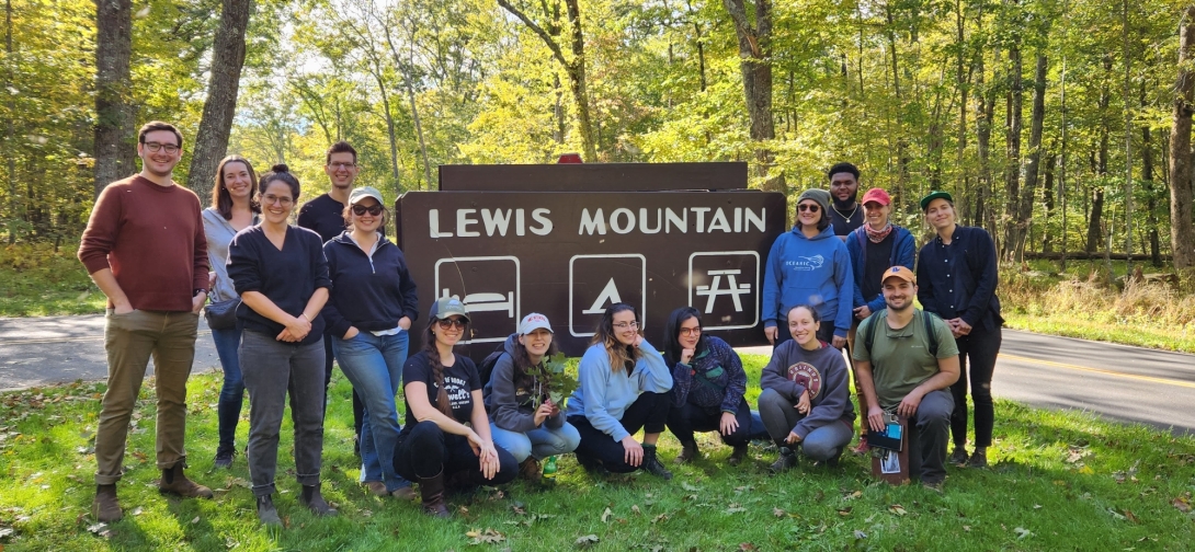 A group of people pose in front of a sign for Lewis Mountain