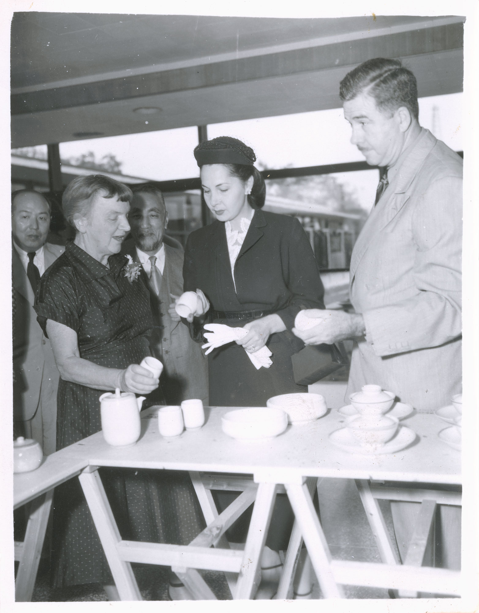 Two women and a man looking at pots