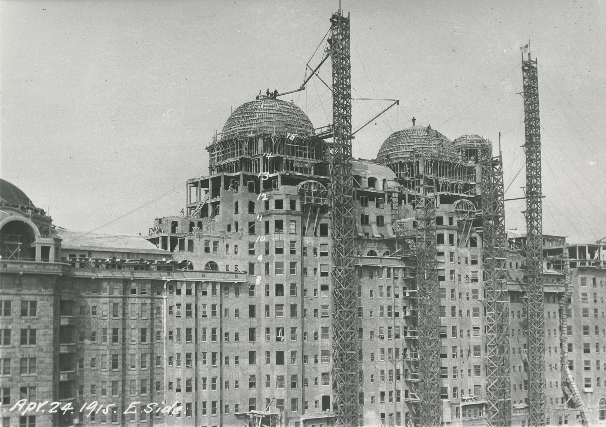 Black and white photograph showing scaffolding on Traymore Hotel, and cranes installing domed roofs