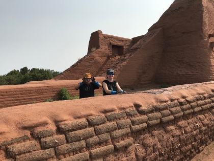 H. Ro and A. Cavicchio applying mud capping on a convento wall, with the Pecos church in the background.