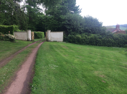 Carriage trail leading to garden entrance framed with two white pillars