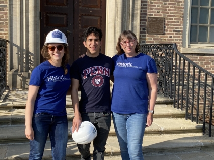 Three people pose in front of brick building