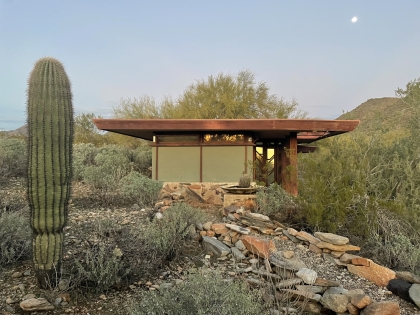 small modernist structure in desert with cactus in foreground