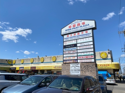 large sign in parking lot of strip mall with yellow awnings