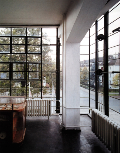 Modernist office with large multipaned windows, antique radiators and curved wooden desk