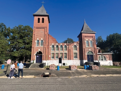 studio team stands in front of partially demolished church