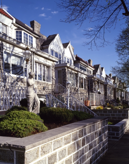 Row houses with brick and wood facades seen against blue sky