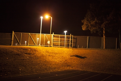 Outdoor art piece featuring a shadow cast by a streetlight that looks like a person.