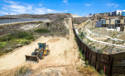 Bulldozer in desert next to fence