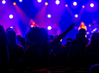 Crowded nightclub, people dancing and bright purple lights flashing.