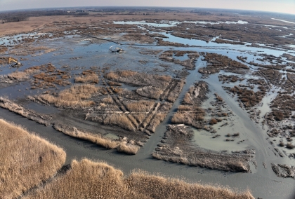 Aerial view of brown marshlike landscape with heavy equipment at work