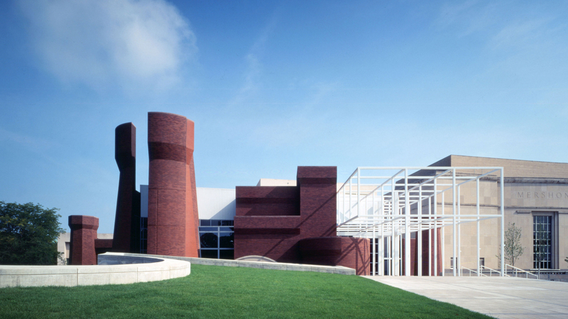 A red brick tower sits next to a cluster of red brick and limestone volumes