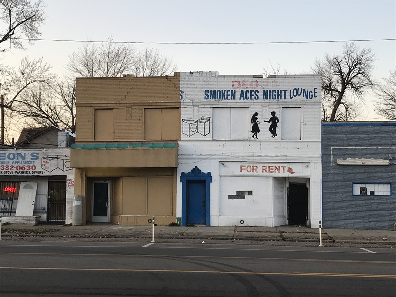  Row of abandoned storefront. One has sign that says "Smokin Aces Dance Hall" and another that says "For Rent"