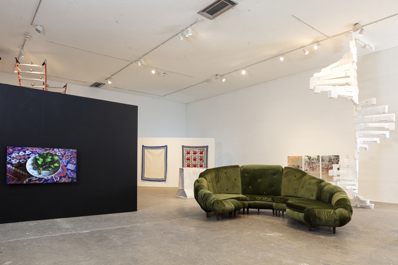 large installation space featuring student work on black and white walls, concrete floor