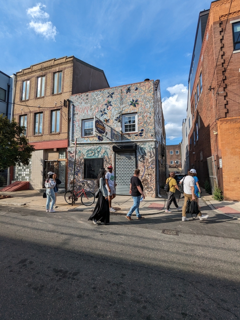 students walk in front of mosaicked rowhouse