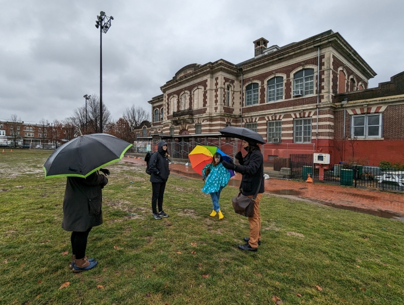 people with umbrellas in grass standing in front of public library