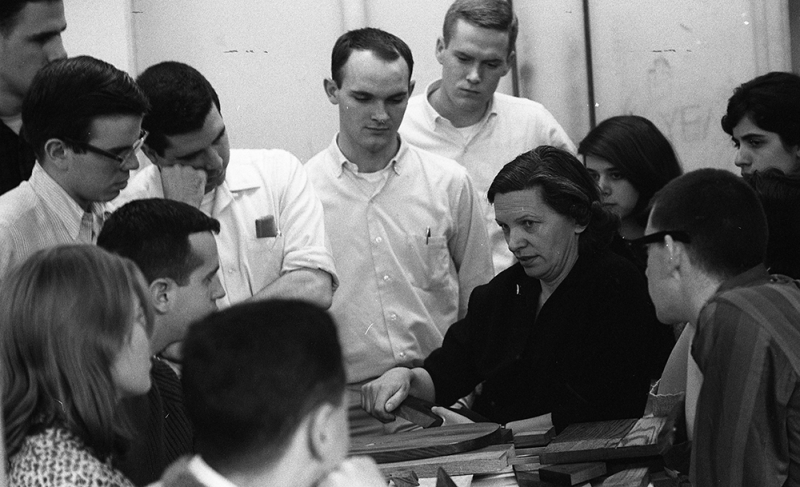 A teacher is surrounded by a group of students