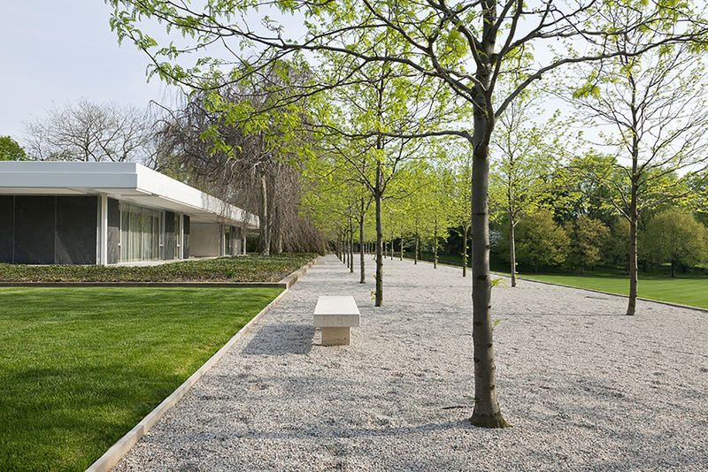 A modernist house with a gravel walkway and bench in front