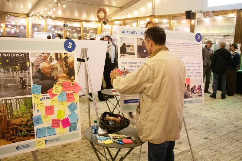 Man putting sticky notes on a poster board in a large conference space