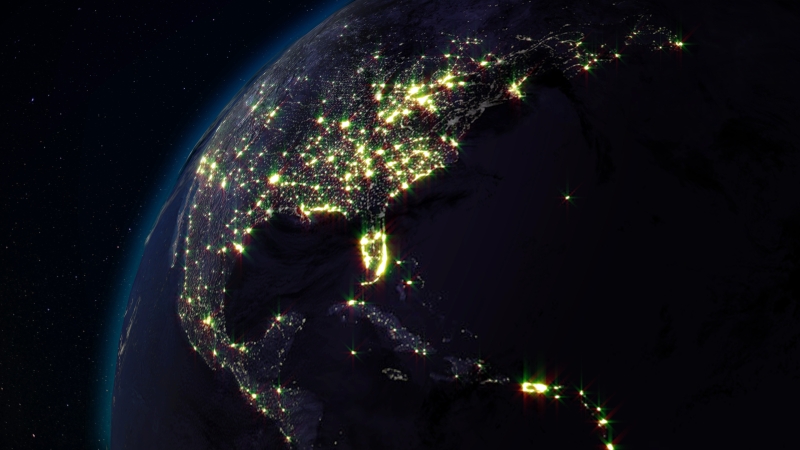 Artist rendering of nighttime view of US from space showing illuminated cities