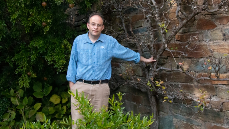 Wunsch standing by bush and tree in blue shirt