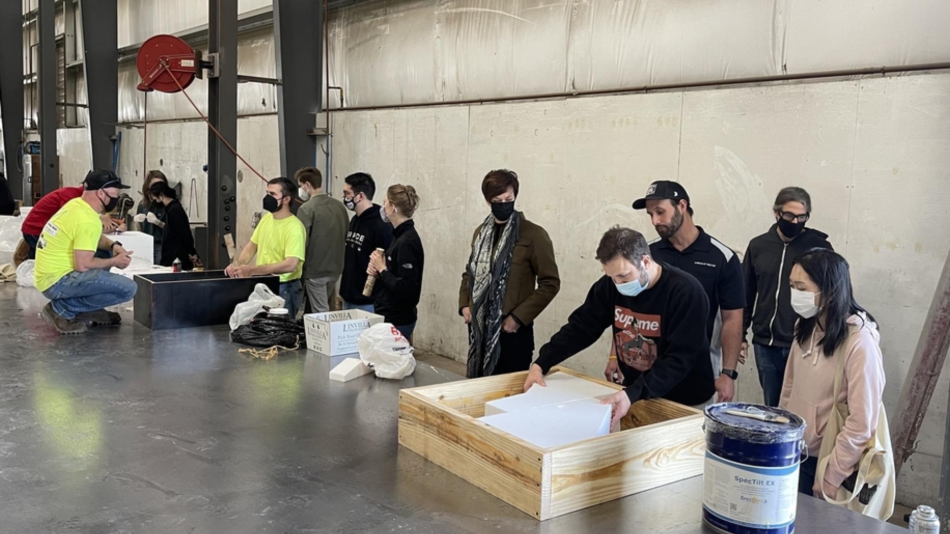 A group of people stand at a table with cast forms in an industrial lab