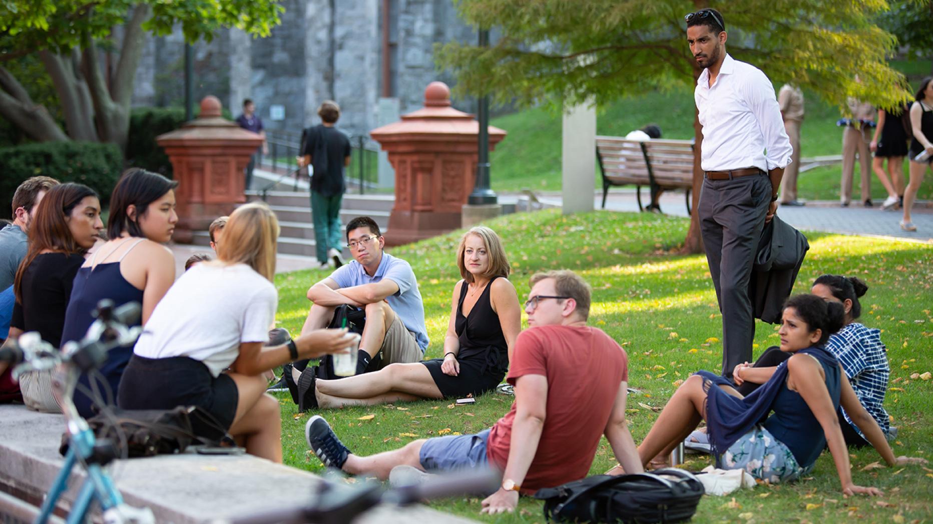 A class meeting outdoors sitting on the grass