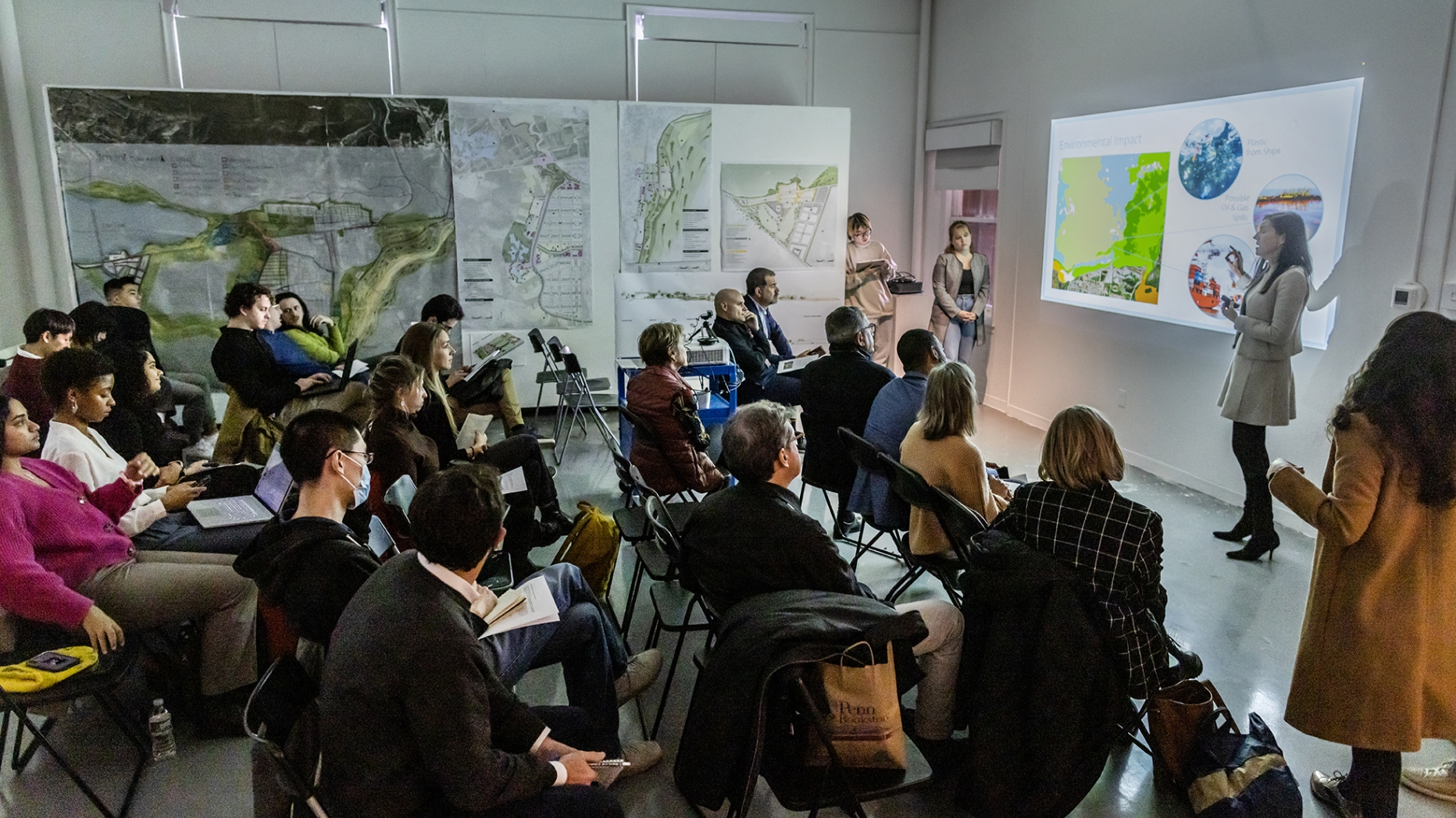 A group of students listening to a presentation by other students 