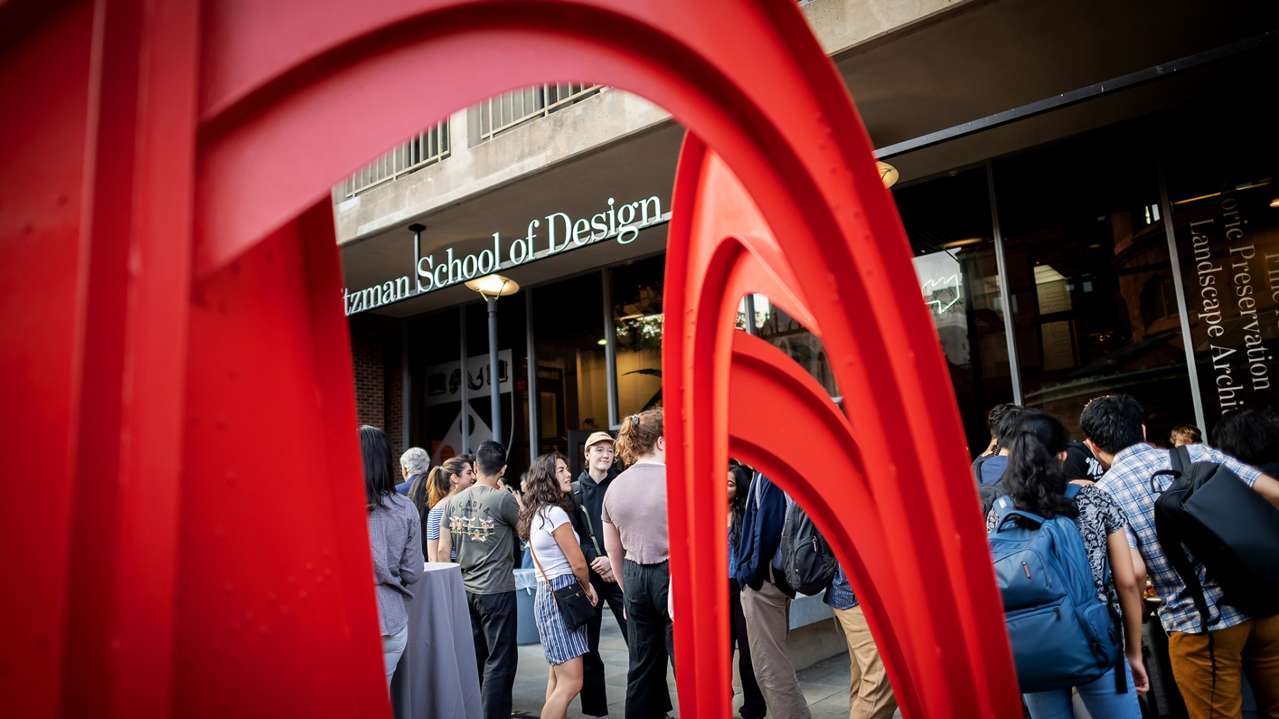 Weitzman students socializing on patio next to red sculpture