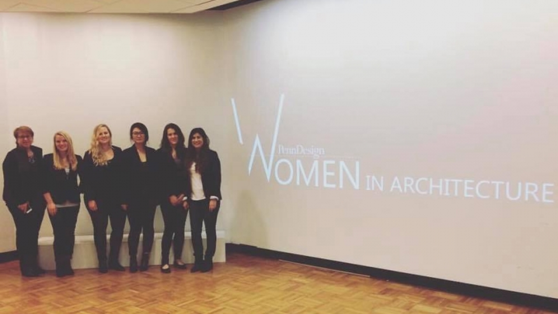 Group of women standing next to a projection saying "Women in architecture"