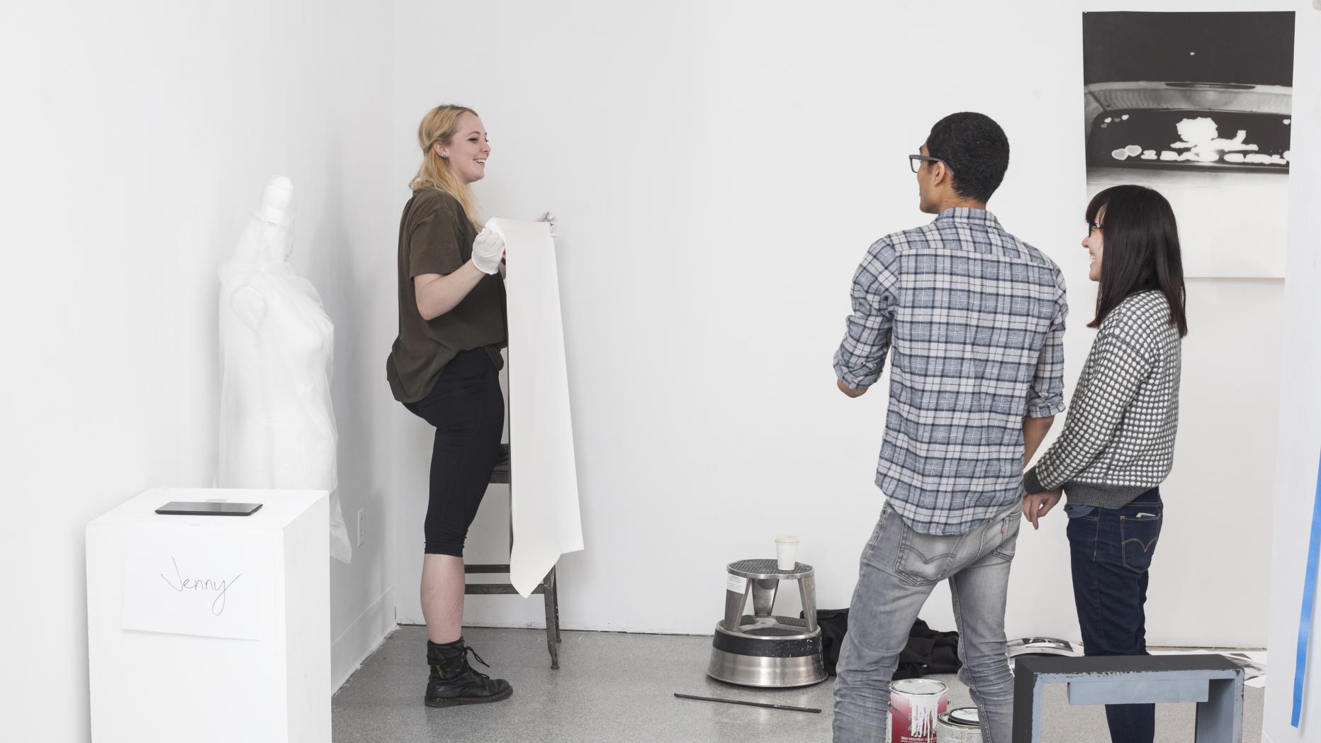 3 students talking while 1 student is working on installation