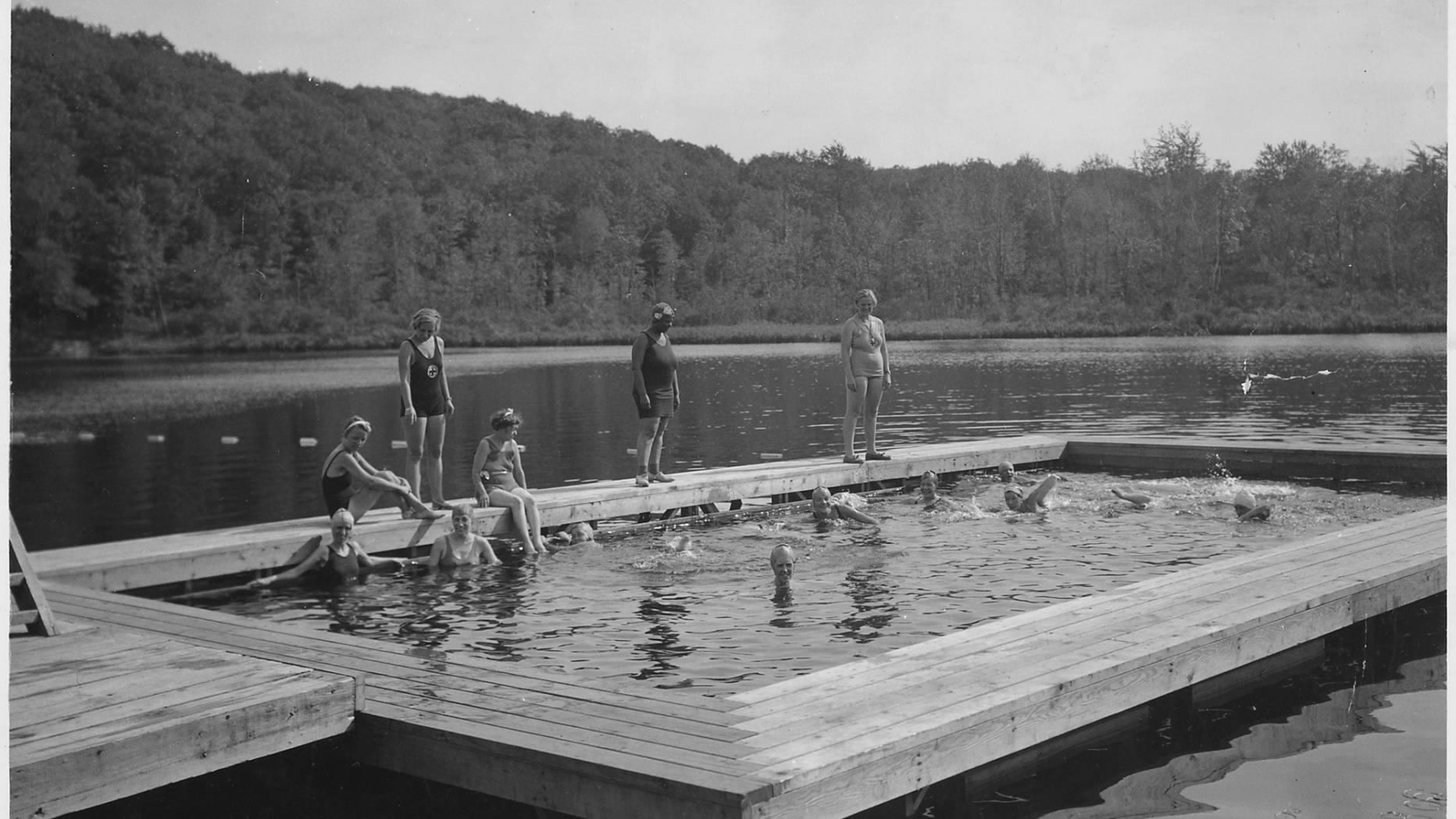 B&W photo of group of people swimming in sectioned of area of lake