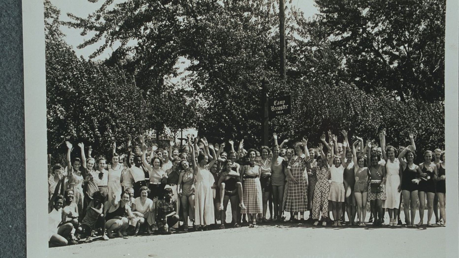 B&W photo of group of young women throwing their arms up in the air for a group photo