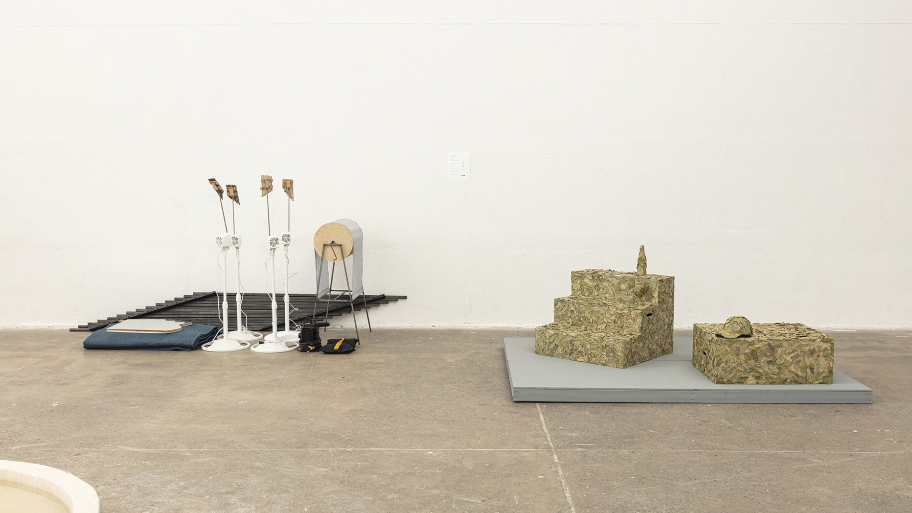 open gallery installation with concrete floor, featuring sculptures by students