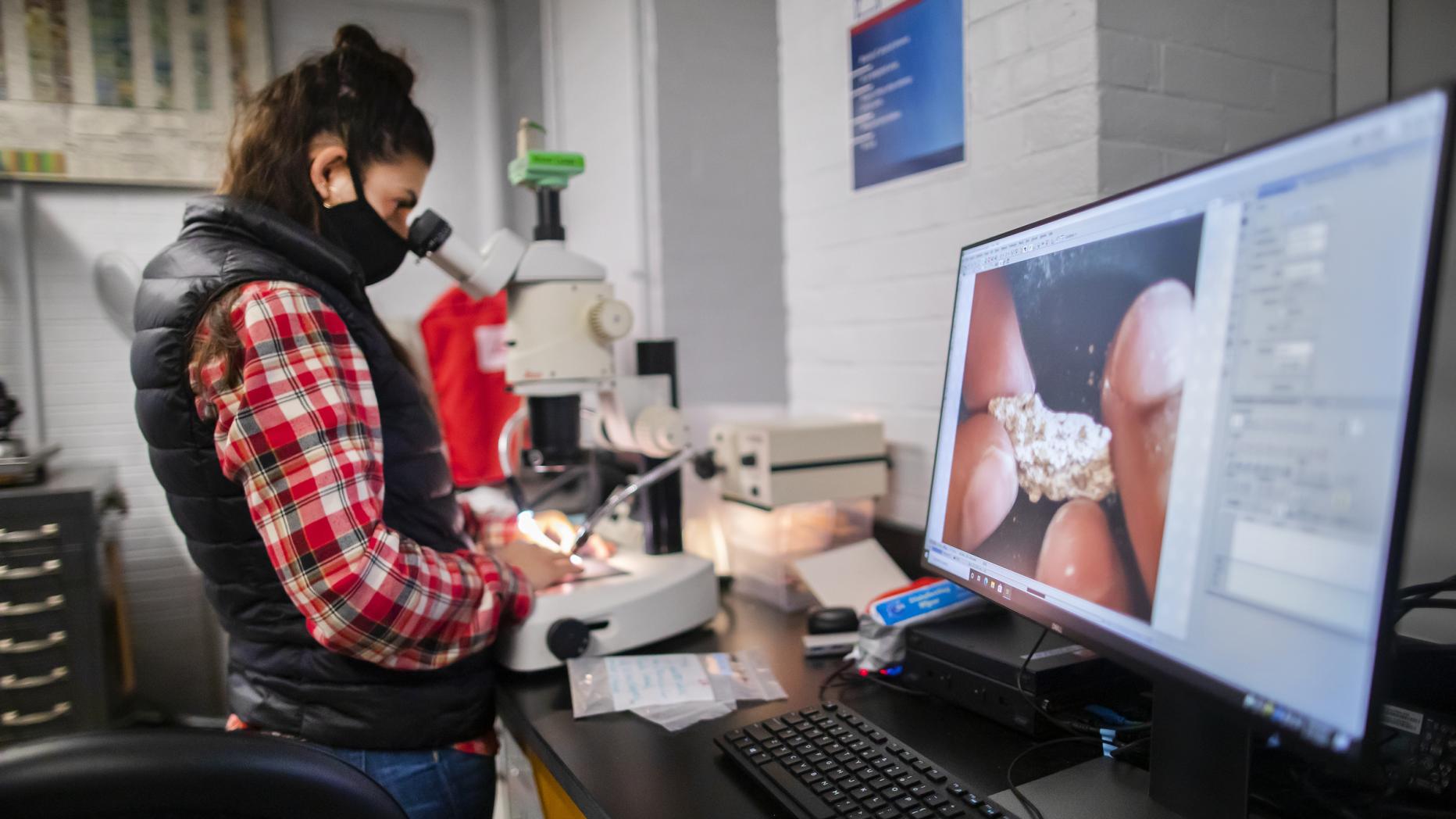 Student looking at a rock under a microscope 