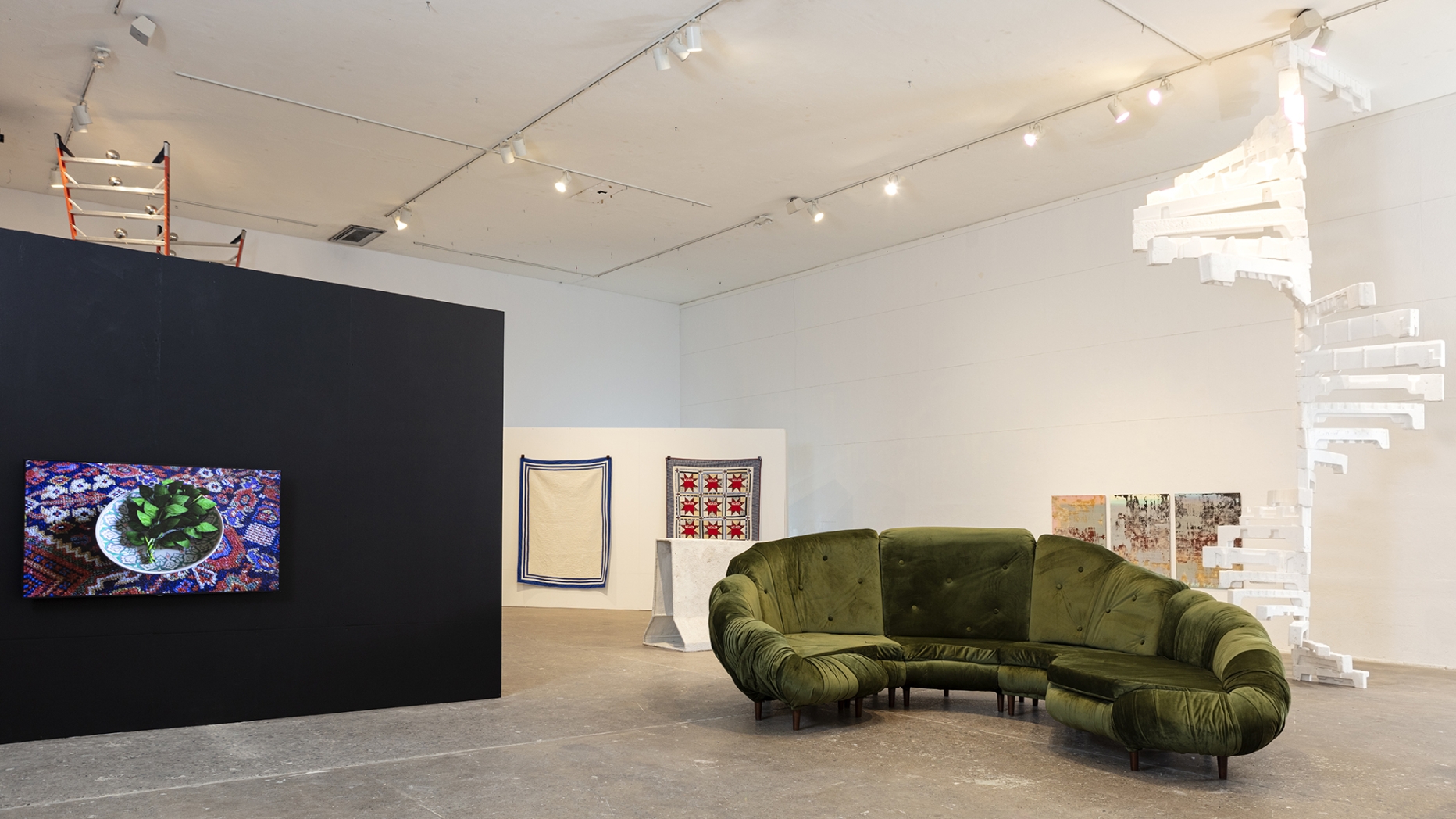 large installation space featuring student work on black and white walls, concrete floor