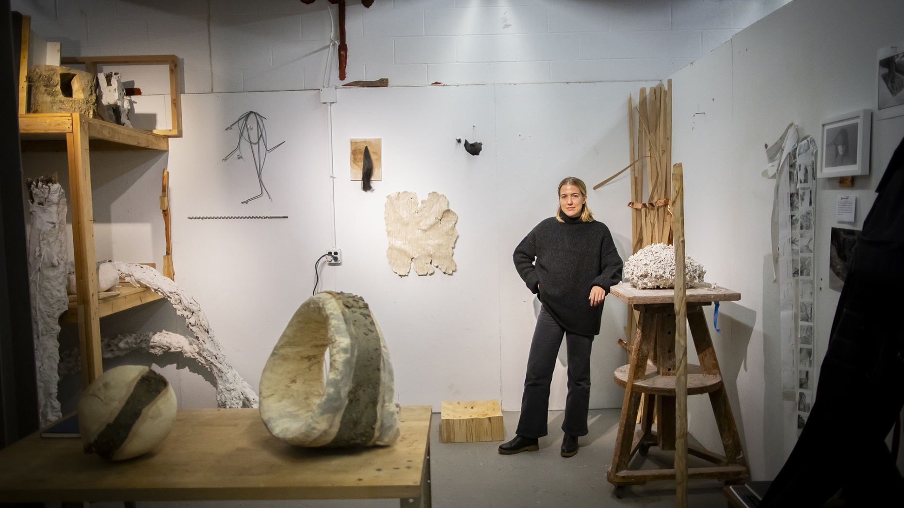 A fine arts student poses in their studio space
