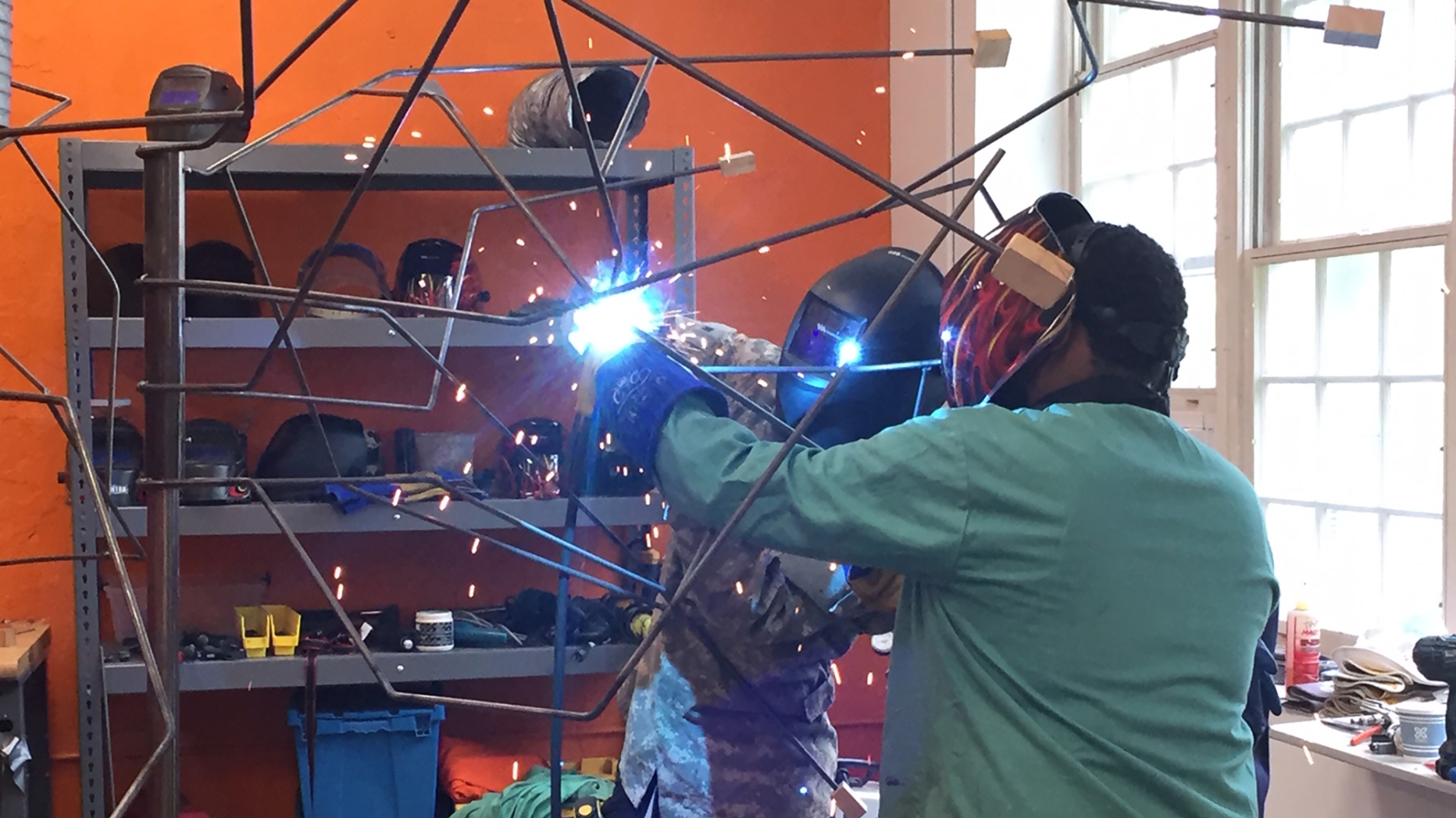 Two students weld parts of a metal structure