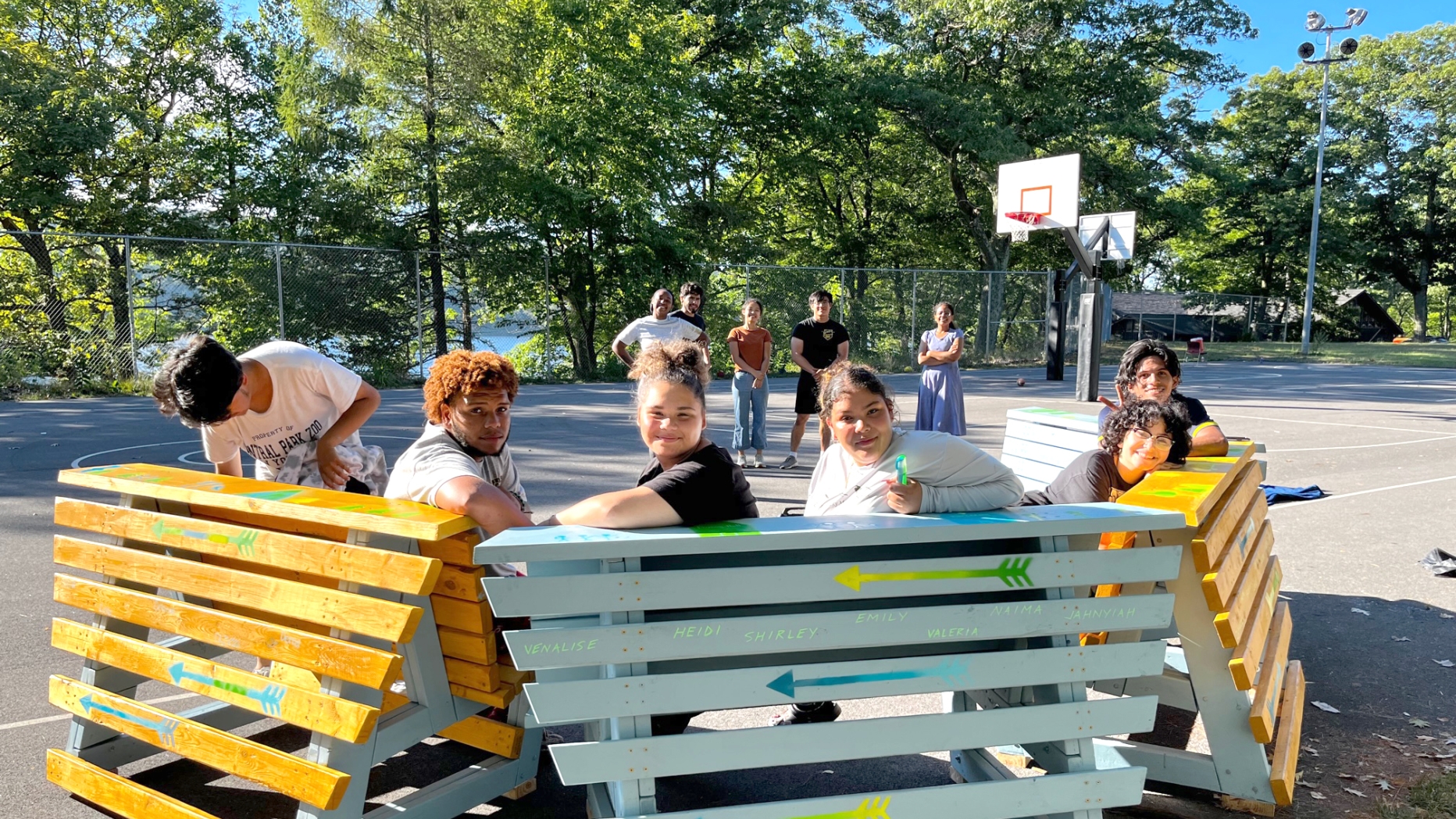 A group of students sitting on benches turn to face the camera