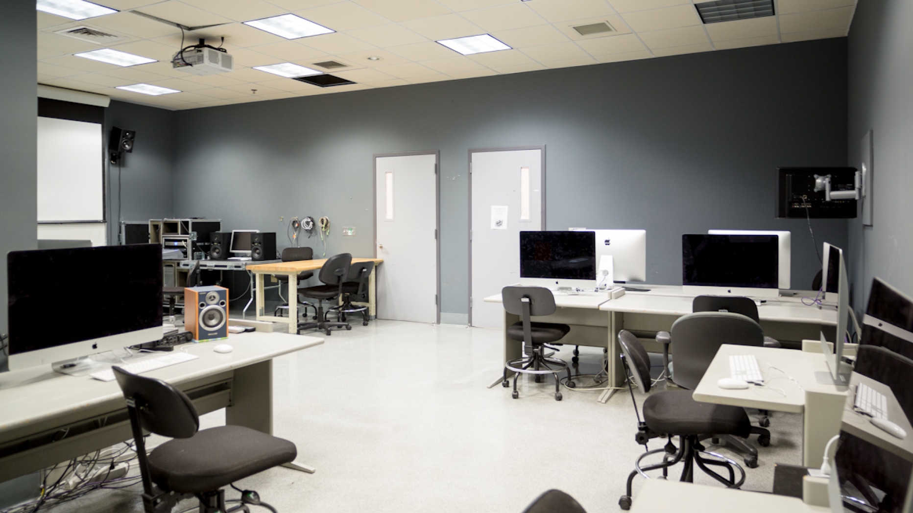 Brightly lit unoccupied computer lab with screen and projector